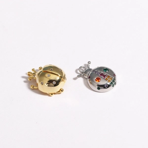 Macro detail of 3D ladybug pendants with gold and silver bases and colorful zircons