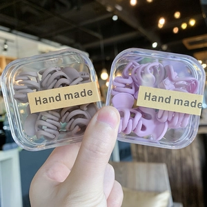 Primer plano de mini pinzas mate para el pelo en marrón y lavanda en cajas transparentes