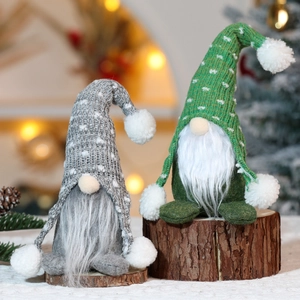 Dettaglio di gnomi natalizi in maglia grigi e verdi su base in legno con luci festose