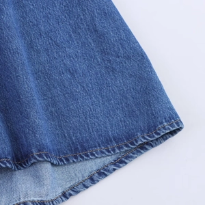 Detailaufnahme von blauem Denim-Stoff mit gelben Nähten und Saumstruktur auf Jeans