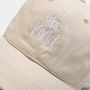 Beige cotton baseball cap featuring white 'be Kind' embroidery and heart detail