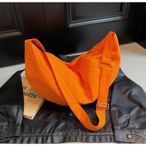 Detail of bright orange nylon crescent bag featuring wide shoulder strap and silver buckle