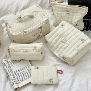 Detailed set of cream quilted storage bags with cute bunny embroidery and gold zippers