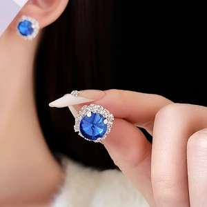 Macro view of French luxury blue round stud earrings with white zircon halo detailing