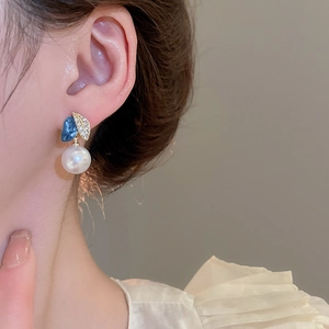 Nahaufnahme von Vintage-Ohrringen mit blauen Harzelementen und Perlen am Modellohr
