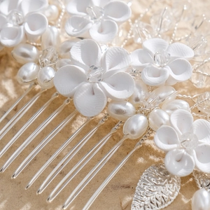 Detailed macro view of white ceramic flowers and faux pearls on silver bridal hair comb