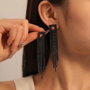 Détail de boucles d'oreilles carrées en strass noirs avec de longues chaînes à franges