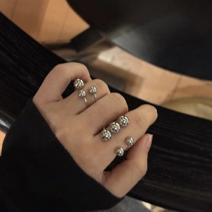 Detailed view of silver spherical stainless steel open rings styled in a trendy layered look