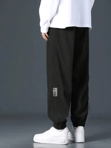 Detail of men's black corduroy cargo pants showing texture and woven ankle label
