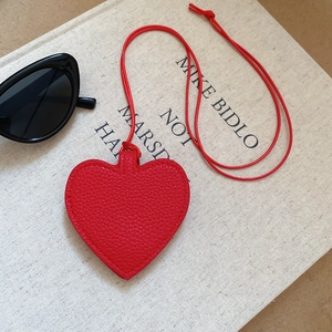 Detail shot of heart-shaped red leather charm with textured grain and delicate stitching