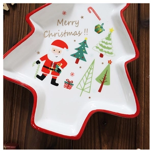Detail of Christmas tree shaped ceramic plate with festive patterns on wood table