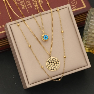 Detail of gold double-layer necklace with blue eye and flower of life pendants on box