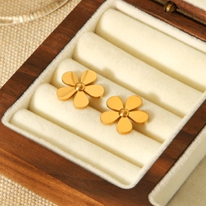 Macro shot of 18k gold floral stud earrings in a wooden jewelry box with velvet lining