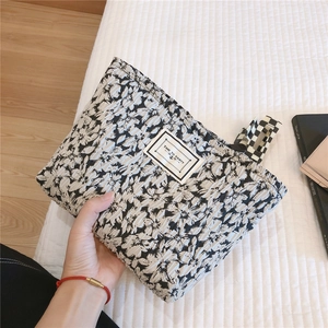 Quilted black and white floral makeup bag with textured fabric and bow accent
