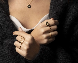 Close-up of model wearing multiple gold geometric rings and star pendant necklace set