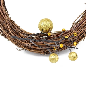 Macro shot of rustic rattan Christmas wreath featuring glittery gold ornaments and berries