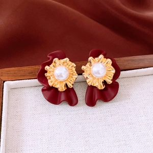 Détail des boucles d'oreilles fleurs rétro avec perle sur plateau en bois et soie