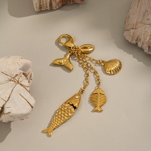 Golden ocean theme keychain with fish bone and shell pendants on natural stone background