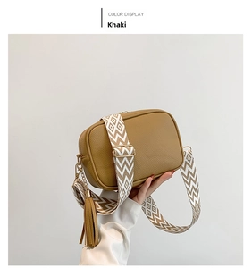 Close-up of khaki crossbody camera bag with diamond pattern strap and tassel detail