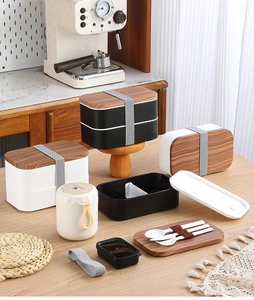 Close-up of dual-layer lunch box set with wood-grain lids and matching utensils
