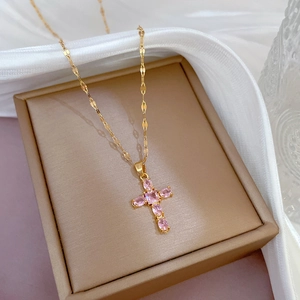 Macro shot of gold cross necklace with pink zircon on a brown jewelry box