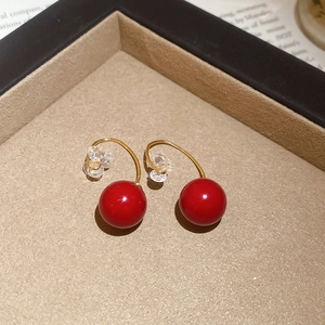 Detail of red cherry resin earrings with gold plating and sparkling crystal accents