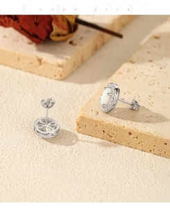 Detail of silver oval opal stud earrings with small zircon stones on textured stone