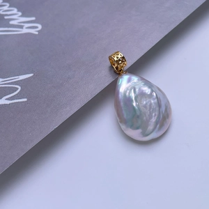 Macro shot of iridescent baroque pearl pendant with decorative gold clasp and luster