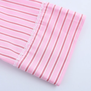 Close-up of pink striped fabric with delicate white lace trim on the sleeve cuff