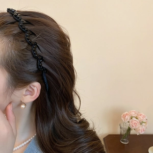 Detail view of a black woven beaded pearl headband worn on elegant brunette wavy hair