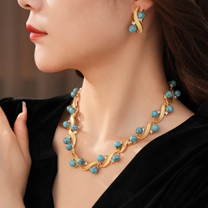 Close-up of vintage gold necklace and earrings set with turquoise and zircon on model