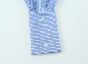Detail shot of blue and white striped shirt cuff with two light blue buttons