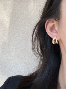 Close-up of gold hollow hoop earring with zircon and brown tigers eye stone on model