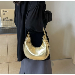 Detail of a shiny gold crescent hobo bag with sleek metallic finish and silver buckle