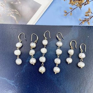 Detailed view of Baroque freshwater pearl drop earrings with elegant gold hooks on blue