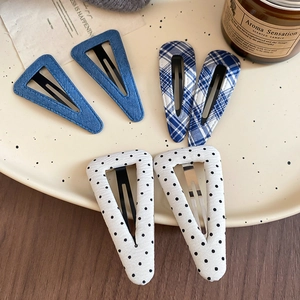 Dettaglio di fermagli a triangolo in tessuto con motivi denim, a quadretti e a pois