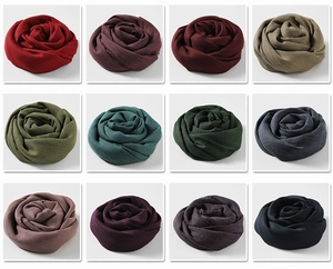 Collection of soft cotton linen scarves in 12 colors rolled into rose shapes on white