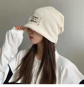 Close-up of cream white ribbed knit beanie with Season 19 woven patch detail