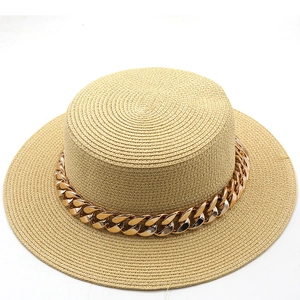 Detailed view of beige straw flat top hat with chunky gold chain decoration