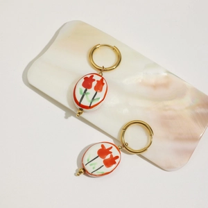 Dettaglio di orecchini a tulipano placcati oro 18K con pendente in ceramica bianca e fiori