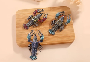Detailed view of lobster brooches with vibrant rhinestones on a wooden tray
