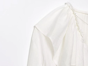 Detailopname van de schouder van deze witte katoen-linnen blouse met ruches en plooien