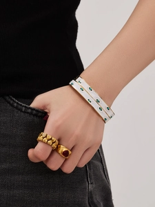 Close-up of enamel evil eye bangles and gold-plated rings set on a female hand