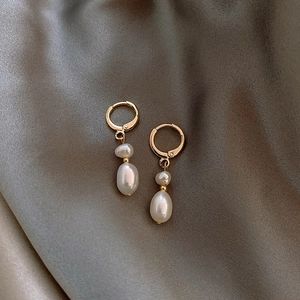 Macro detail of French style baroque freshwater pearl drop earrings on silk fabric