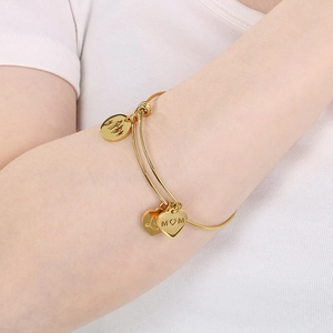 Detail of adjustable gold MOM bracelet with heart charms on model's wrist