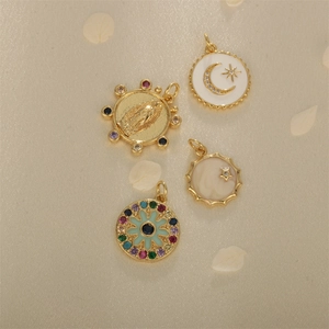 Gold plated charms with star, moon and heart designs on beige silk fabric background