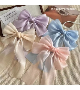 Flat lay of macaron-colored mesh bow hair clips with long ribbons and elegant pearl accents