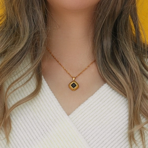 Detail of gold twisted chain necklace with square black gemstone pendant on model