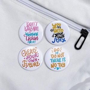 Macro detail of four motivational tinplate badges pinned on white canvas bag surface