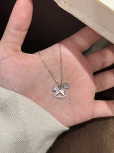 Gros plan d'un collier cheval à bascule argenté avec nacre et zircons.